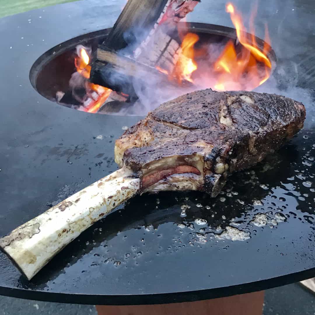 a large tomahawk ribeye grilling on an Arteflame grill