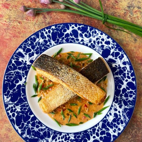picture of salmon with cajun cream sauce on a decorative blue and white plate