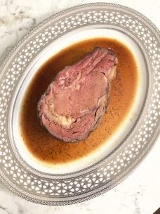 A slice of cooked prime rib on a plate cooked to a perfect medium-rare.
